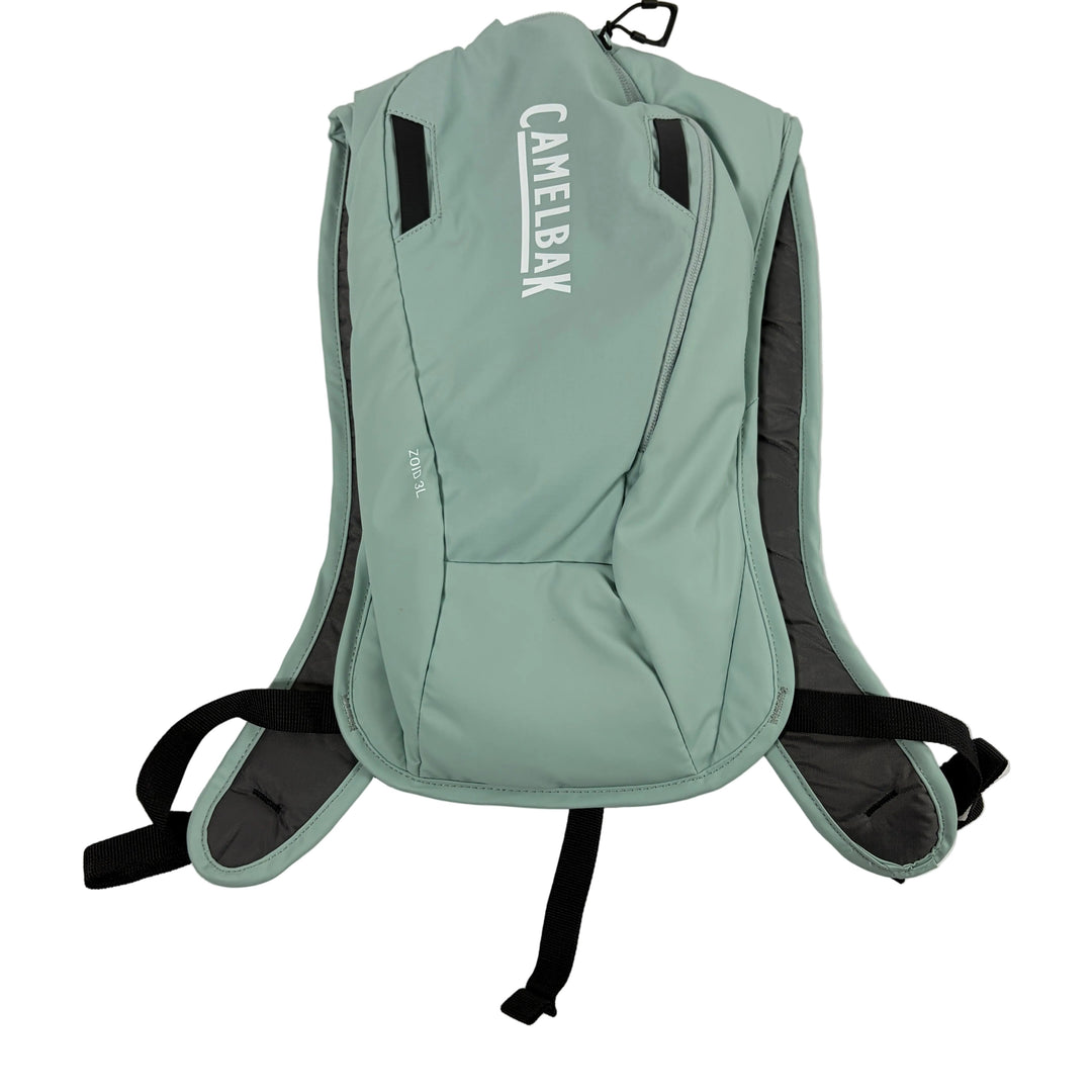 A sage green CamelBak hydration pack with black straps and gray padding, shown from the back against a plain white background.