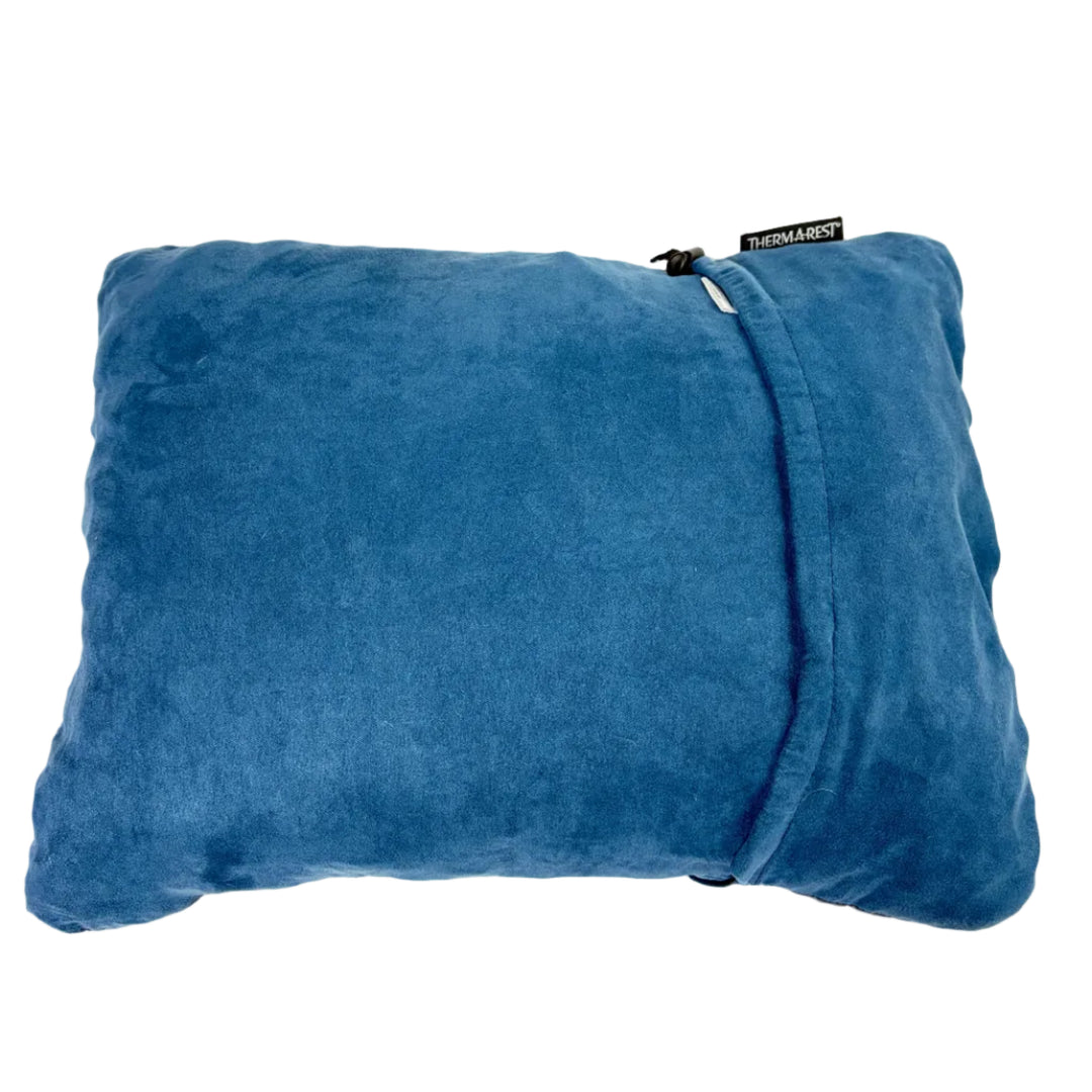A blue plush throw pillow with a zippered closure, featuring a small black fabric tag on the upper right side that reads 'THEMANTY'. The pillow is photographed from a top-down perspective against a clean, off-white background.