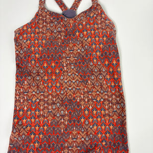 A sleeveless halter-style top with a dense geometric and tribal-inspired pattern in red, orange, brown, and blue, displayed flat against a light gray background.